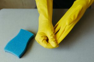 Person Wearing Yellow Cleaning Gloves and Sponge
