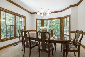 A spacious dining room with wooden furniture and large windows overlooking a green landscape.